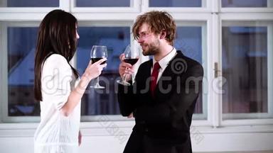 年轻浪漫的一对夫妇喝着红酒庆祝。 浪漫的夫妇喝红酒。 漂亮的年轻夫妇